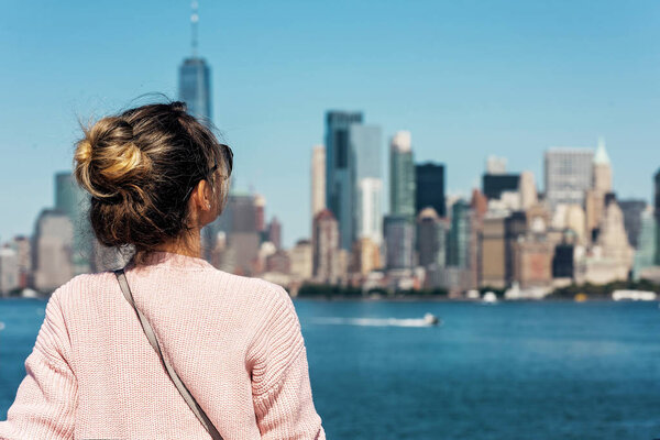 Woman in pink sweater posing on the background of New York city skyline, USA