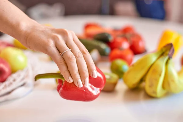 Mãos de mulher segurando pimenta vermelha com outras frutas no fundo — Fotografia de Stock