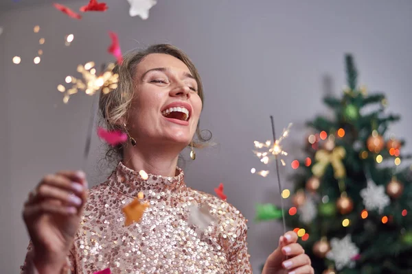Woman smiling into the camera with christmas tree on background