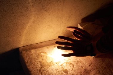 Erkek eli sarı ampule dokunuyor.