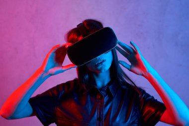 Ceket giyerken sanal gerçeklik kaskı kullanan genç bir kız.