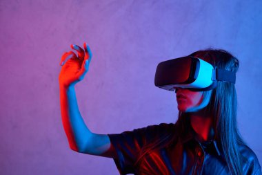 Ceket giyerken sanal gerçeklik kaskı kullanan genç bir kız.