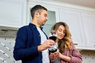 Mutfakta şarap bardakları tutan güzel bir çift.