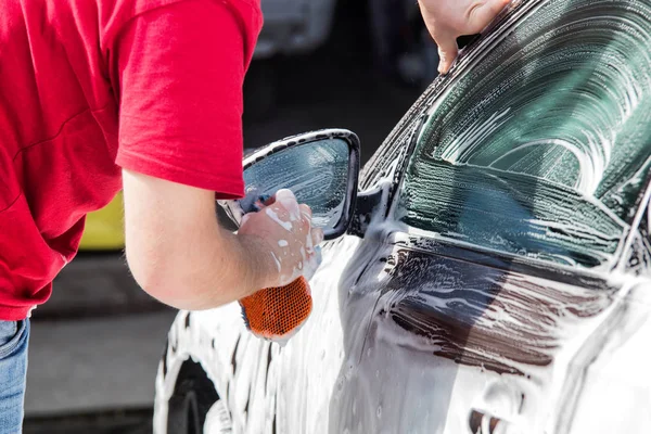 Manual car wash. Man washing his car.