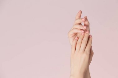 Kadın temiz cilt ile elleri ve pembe Lehçe manikür üzerinde pembe bir arka plan ile çivi. Tırnak bakımı ve güzellik Tema. Güzellik arka plan kopya alanı ile.