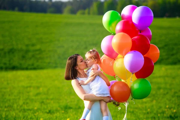 年轻的妇女与孩子在白色礼服与五颜六色的气球户外 妈妈亲女儿快乐的家庭享受新鲜的夏日空气 — 图库照片