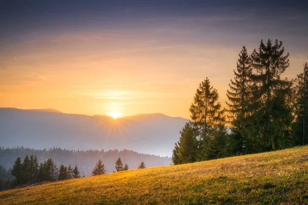 Slunce se dotýká vrcholku hory na jasné večerní obloze — Stock fotografie