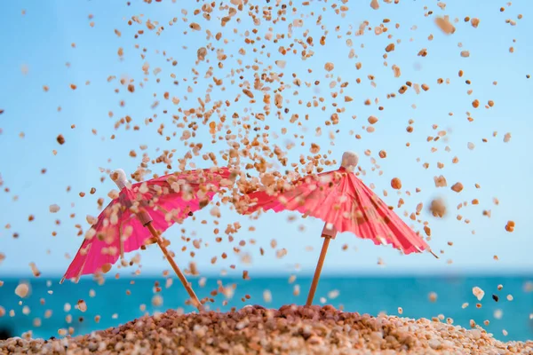 Red umbrellas on a beach with sand grains. Beach by the sea, turquose water color.