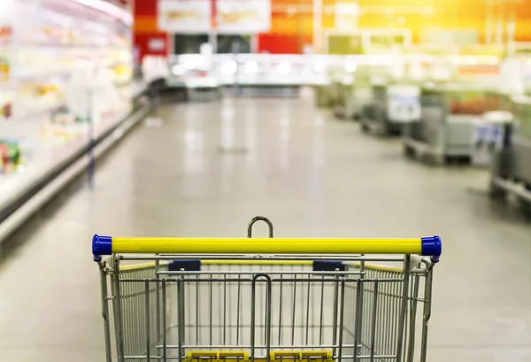 Cart at the grocery store. Abstract blurred photo of store with trolley in department store bokeh background. New ideas in trade and business.Advertising of food products. Shopping at the hypermarket.