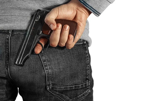 A man holding a gun in his hand behind his back, close-up view. Concepts: crime, attempted murder, a gunshot wound, the killer. Isolated background. — Stock Photo, Image