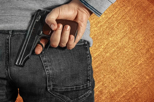 Ein Mann mit einer Waffe in der Hand hinter seinem Rücken, Nahaufnahme. Begriffe: Verbrechen, versuchter Mord, eine Schusswunde, der Mörder, Raub. — Stockfoto