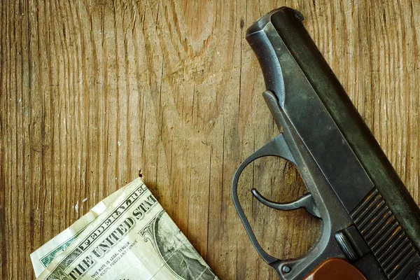 The gun and money on wooden table. Concepts: crime, contract killing, killer, robbery, extortion, money laundering. — Stock fotografie