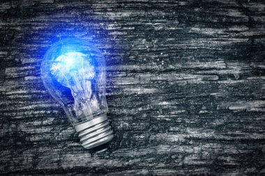 Yanan ampul karanlık eski ahşap arka plan üzerinde. Yeni iş fikri ve ticaret yenilik. Satış, satın alma ve reklam. Çevre dostu enerji kaynakları. Enerji alternatif formları.