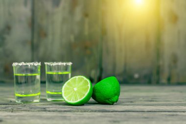 Gözlük kireç dilimleri ile altın Meksika tekila ile vuruldu ve eski ahşap masada tuz. Seçici odak. Geleneksel Meksika içki. Alkollü içecek. Kopya alanı ile kapatın. Vintage tasarım.