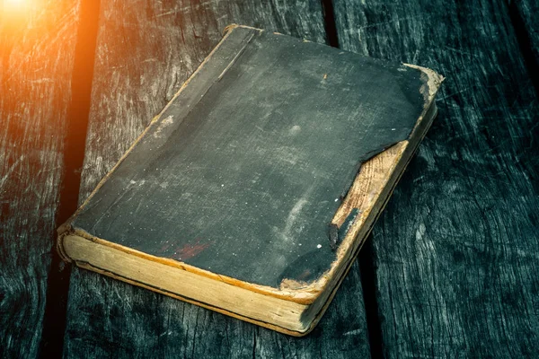 Oude gescheurde boek over een houten tafel. Lezing bij kaarslicht. Vintage samenstelling. Oude bibliotheek. Antieke literatuur. Fantastische sfeer. Middeleeuwse en mystieke achtergrond, vintage style, religie. — Stockfoto