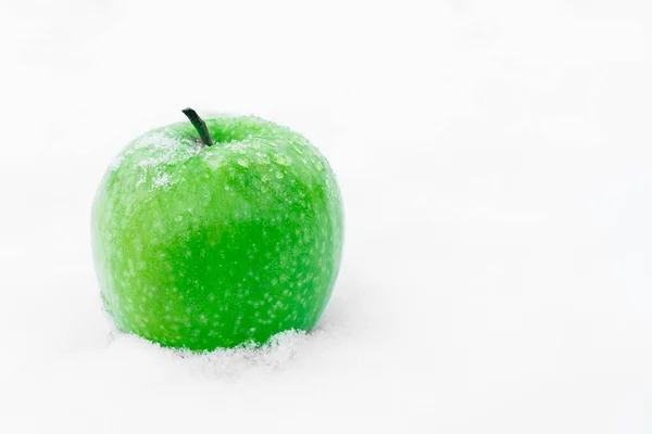 Zielone jabłko w śniegu. Piękny zimowy skład. — Zdjęcie stockowe