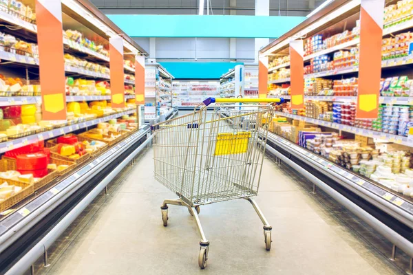 Cart at the grocery store. Supermarket interior, empty shopping trolley. Business ideas and retail trade. Advertising of food products.