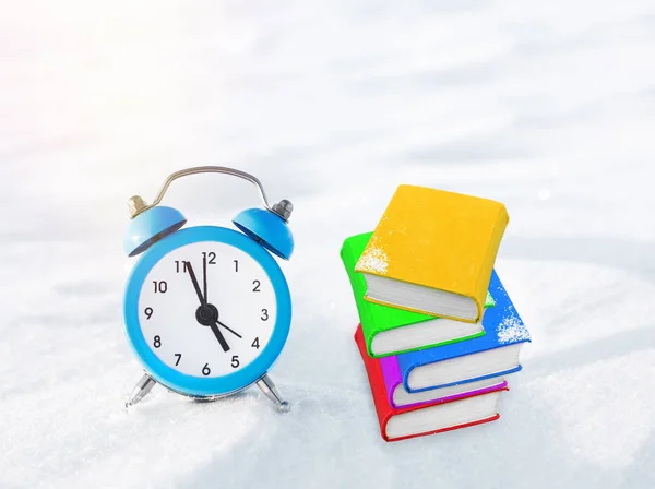 时间来阅读。书和老式的闹钟在雪地上。圣诞节和新年的概念。神奇的组合。切换到冬天的时候。早上好。等待的假期。在考试的期待 — 图库照片