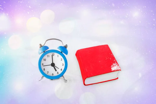时间来阅读。书和老式的闹钟在雪地上。圣诞节和新年的概念。神奇的组合。切换到冬天的时候。早上好。等待的假期。在考试的期待 — 图库照片