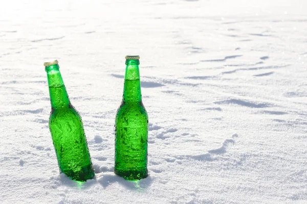 Две бутылки холодного пива на снегу на закате. Закрыть вид . — стоковое фото