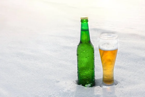 Krug und Flasche kaltes Bier im Schnee bei Sonnenuntergang. schöner Winterhintergrund. Freizeitaktivitäten. Werbung für alkoholische Getränke. — Stockfoto