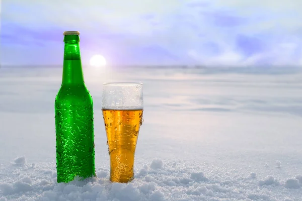 Taza y botella de cerveza fría en la nieve al atardecer. Hermoso fondo de invierno. Recreo al aire libre. Publicidad de bebidas alcohólicas . —  Fotos de Stock