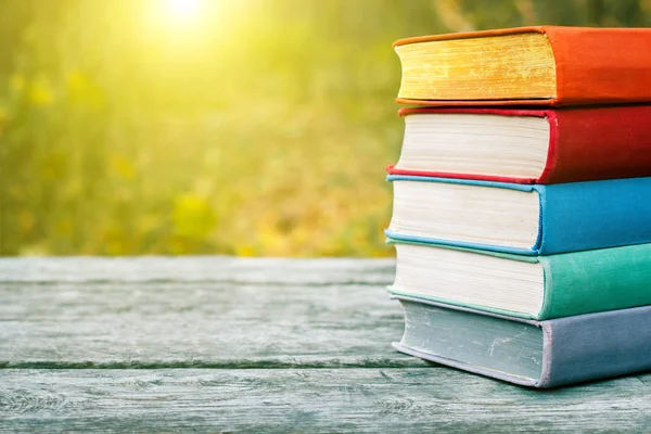 Boeken over de oude houten tafel op de achtergrond van de natuur. — Stockfoto