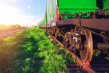 Gün batımında tren istasyonu. Yeşil çim ve mavi gökyüzü. Trafik ışıkları demiryolu üzerinde yeşil, kırmızı sinyal gösterir. Bir yük treni araçların kapatın. Tren. Demiryolu Taşımacılığı.