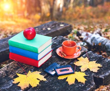 Books and a cup of hot coffee with cinnamon on the table in the forest at sunset. Vintage style. Back to school. Education concept. Beautiful autumn background. Weekend in the park. clipart