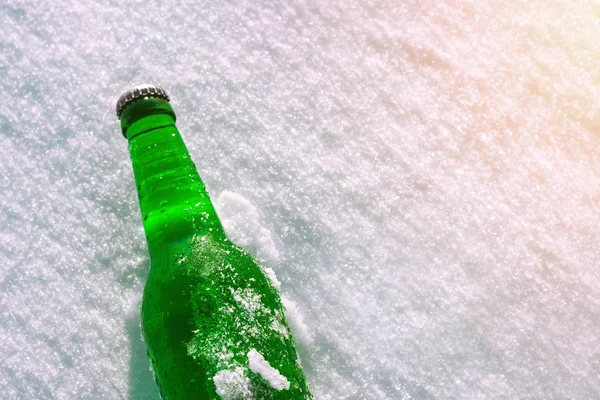 Bottle of cold beer on the snow. Close up view.