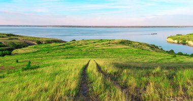 Tepelerin üst deniz doğal manzara. Güzel yaz arka plan. Muhteşem manzara sarı çayır, yeşil ağaçlar, mavi gökyüzü, dik kayalıklarla ve pitoresk Körfezi ile. Panoramik fotoğraf. Kamp, dinlenmek, dinlenmek.