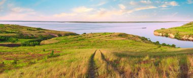 Tepelerin üst deniz doğal manzara. Güzel yaz arka plan. Muhteşem manzara sarı çayır, yeşil ağaçlar, mavi gökyüzü, dik kayalıklarla ve pitoresk Körfezi ile. Panoramik fotoğraf. Kamp, dinlenmek, dinlenmek.
