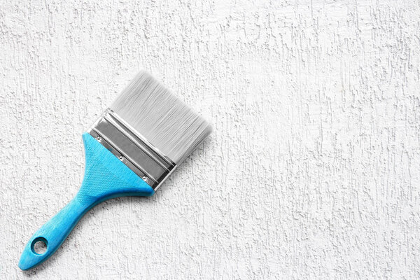 Paint brush on the white rough surface. Construction tool.