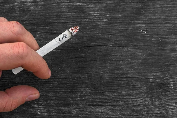 Jovem segurando um cigarro na mão. Conceito de dependência do tabaco e o perigo de fumar. Consequências da dependência da nicotina. Hábito nocivo. Destruição do corpo humano. Vista de perto . — Fotografia de Stock