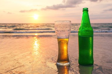 Bir bardak soğuk bira batımında deniz kıyısında. Kumsalda dinlenmek.