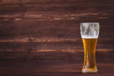 Bardak kahverengi ahşap arka plan üzerinde soğuk bira.