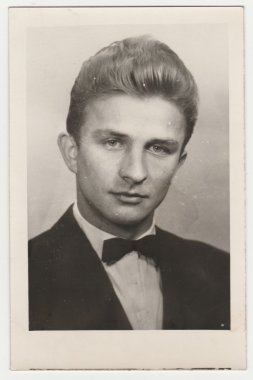 Vintage fotoğraf genç bir adam gösterir. O siyah ceket ve kravat takıyor. Stüdyo portre. Retro siyah ve beyaz fotoğraf.