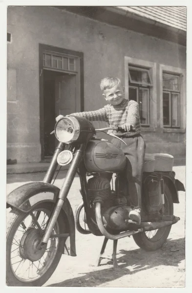 Vintage photo shows boy sits on the vintage motorcycle.  Retro black & white  photography. — Stock Photo, Image