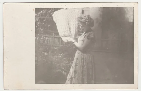 Vintage photo shows a young woman  hangs a woolly vest on a clothesline. Retro black & white  photography. — Stock Photo, Image