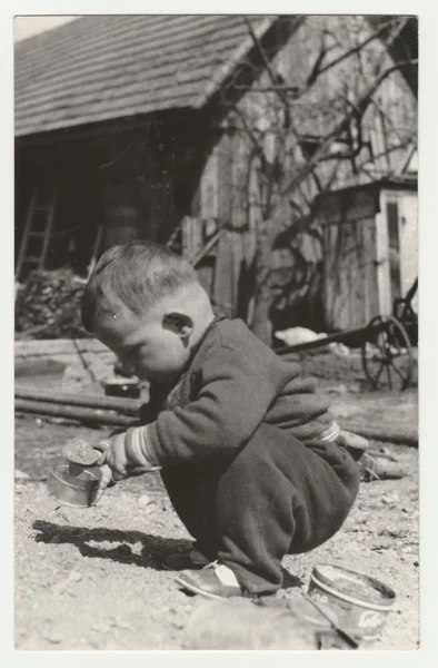 Foto vintage mostra um menino pequeno joga no quintal. Retro preto & fotografia branca . — Fotografia de Stock