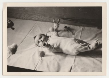 Vintage Fotoğraf yeni bir oyuncak bebek yalanlarla tarihi gösterir. Retro siyah ve beyaz fotoğraf.