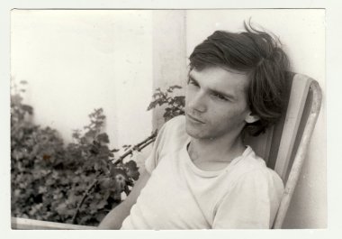 Vintage Fotoğraf bir genç çocuk açık havada kamp sandalyeye oturur gösterir. Retro siyah ve beyaz fotoğraf.