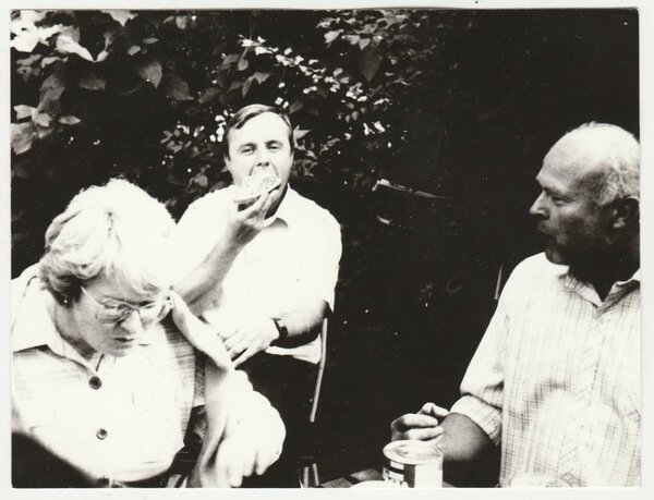 Vintage photo shows people have a snack outdoors. Retro black & white  photography.