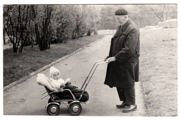Винтажное фото показывает дедушку с маленьким ребенком в коляске (коляске). Черно-белая фотография Retro — стоковое фото
