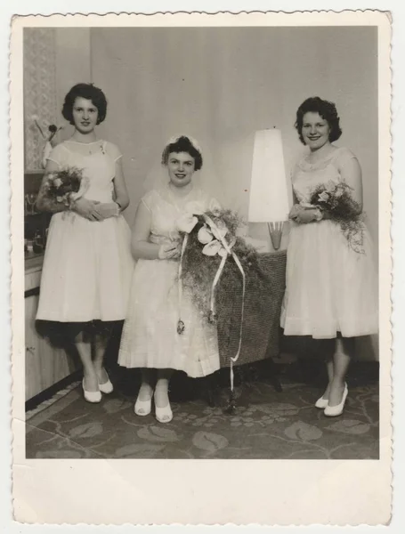 老式照片显示新娘与伴娘。新娘穿着柔软的面纱，持有马蹄莲花 （束）。复古的黑色与白色摄影. — 图库照片