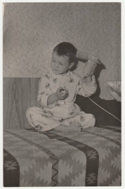 Vintage Fotoğraf küçük bir çocuk pijama giyiyor ve saç kurutma makinesi kullandığını gösterir. Komik fotoğraf şirin bir çocuk. Retro siyah ve beyaz fotoğraf.