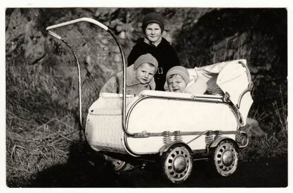 Vintage fotografie ukazuje malé děti a dítě v kočárku (silniční) v zimě. Retro černé & bílé fotografie. — Stock fotografie