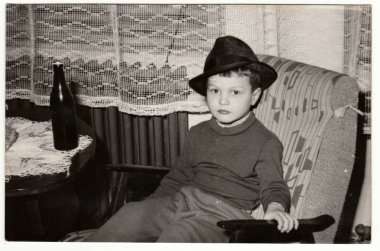 Vintage Fotoğraf küçük bir çocuk ile bir şişe bira gösterir. Komik ve sevimli çocuk fotoğrafı. Retro siyah ve beyaz fotoğraf.