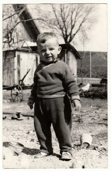 Vintage photo shows a small boy stands in the backyard.  Retro black & white  photography. — Stock Photo, Image