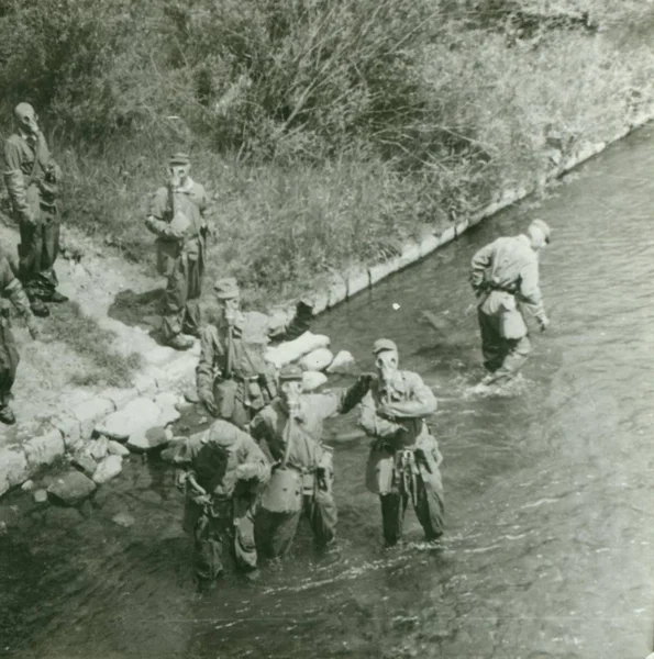 Retro-Foto zeigt junge Männer (Soldaten) während einer Armeeübung. Soldaten mit Gasmasken auf dem Kopf. Oldtimer-Fotografie. — Stockfoto